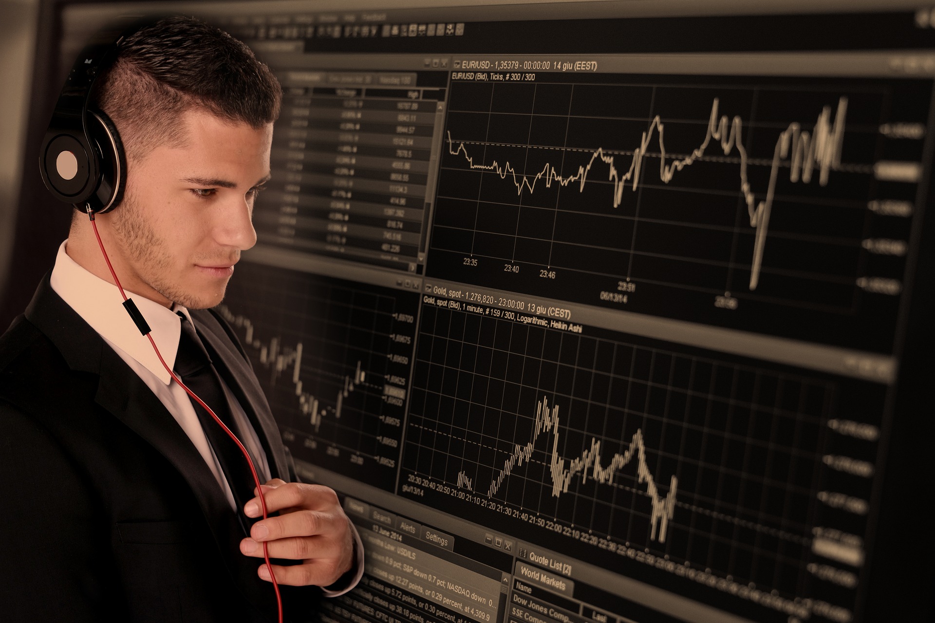 Zdjęcie przedstawiające młodego mężczyznę pracującego przy monitorach z wykresami walut - Pixabay