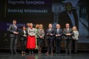 Grupa kilkunastu najważniejszych gości Konferencji, elegancko ubranych kobiet i mężczyzn, stoi na scenie Opery Krakowskiej i pozuje do okolicznościowego zdjęcia.