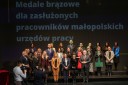Grupa kilkudziesięciu odznaczonych osób stojąca w 3 rzędach pozuje do zdjęcia z wicewojewodą Ryszardem Pagaczem i dyrektorem WUP Arkadiuszem Psicą.