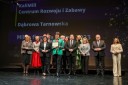 Grupa kilkunastu najważniejszych gości Konferencji, elegancko ubranych kobiet i mężczyzn, stoi na scenie Opery Krakowskiej i pozuje do okolicznościowego zdjęcia. Jedna z nich trzyma statuetkę i  okolicznościową tabliczkę.