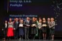 Grupa kilkunastu najważniejszych gości Konferencji, elegancko ubranych kobiet i mężczyzn, stoi na scenie Opery Krakowskiej i pozuje do okolicznościowego zdjęcia. Wśród nich są nominowani do nagród.