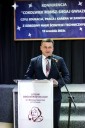 Elegancko ubrany mężczyzna przemawia zza mównicy. To Wojciech Skruch Wiceprzewodniczący Sejmiku Województwa Małopolskiego.