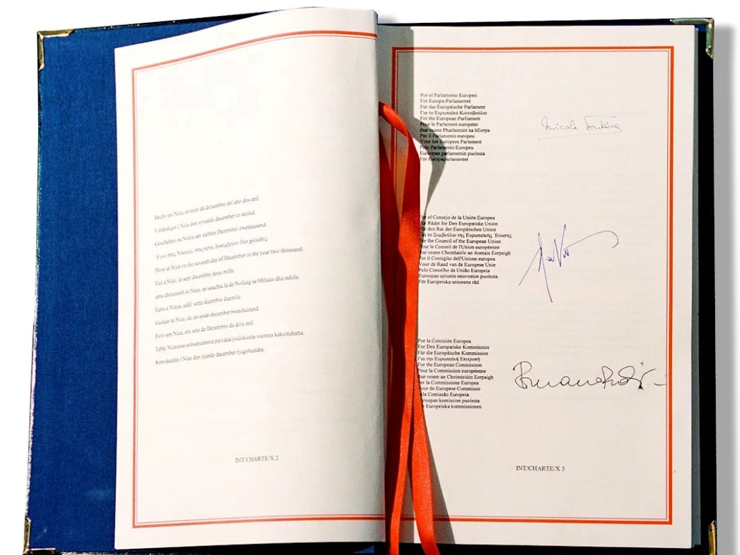 Otwarta gruba księga na stronie zawierającej podpisy. To egzemplarz Karty Praw Podstawowych.