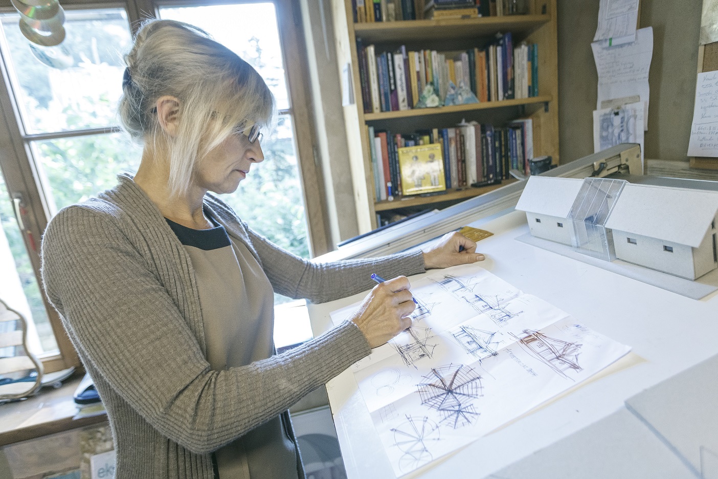 Dojrzała kobieta rysuje przy desce kreślarskiej